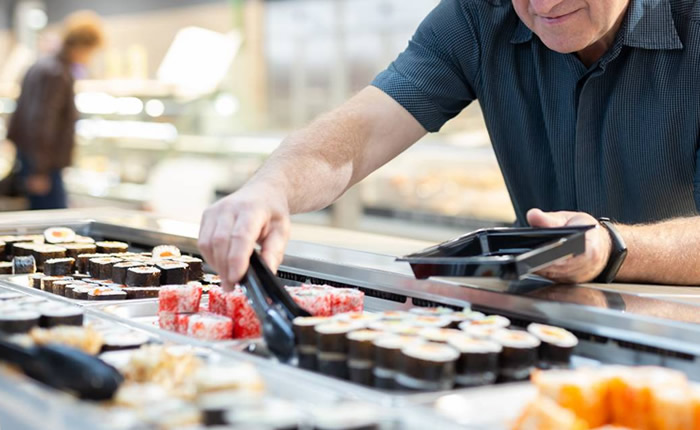 スーパーの惣菜コーナーでSUSHIを取る男性